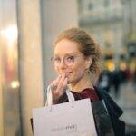 A stylish woman shopping in Milano's fashion district, holding bags and smiling.